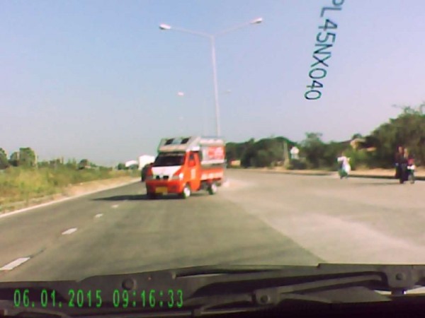 Songtaew crossing into oncoming traffic.